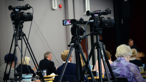 Kameror på stativ som filmar kommunfullmäktiges sammanträde.
