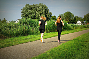 Två personer på joggingrunda längs med gröna naturytor.
