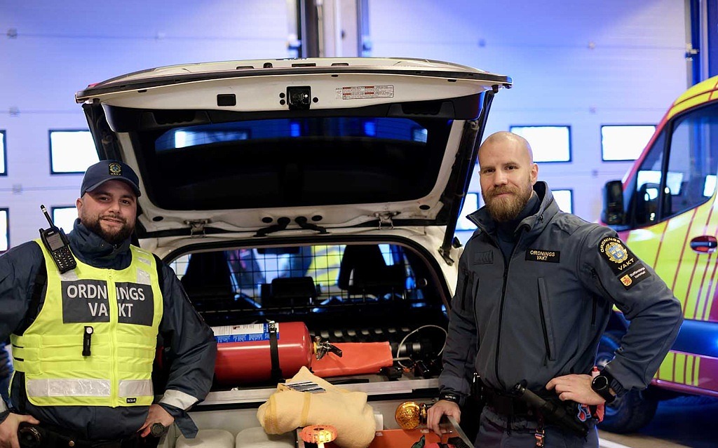Två ordningsvakter framför ett av säkerhetsenhetens fordon.